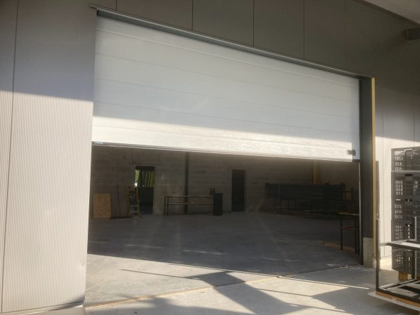 Porte roulante ouverte d'un entrepôt avec un espace dégagé à l'intérieur.