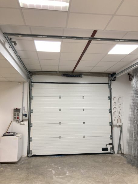 Intérieur d'un garage avec porte de garage blanche et plafond lumineux.