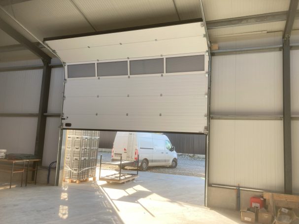 Porte de garage ouverte avec un véhicule blanc à l'extérieur.